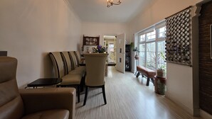 A hallway with a sofa, chairs, a table, a chandelier, a mirror wall, and a door leading to another room.