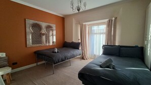 A bedroom with a bed, a chair, a decorative wall piece, and a window with curtains.