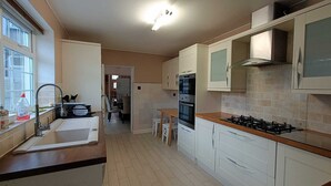 A modern kitchen with white cabinets, a gas stove, an oven, and a window with a view.
