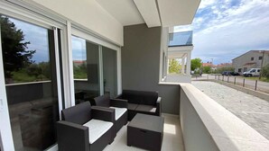 A balcony with outdoor furniture, a glass door, and a view of the street. - Holiday Apartment APARTMENT EMANUEL (4+1) (Vodice)