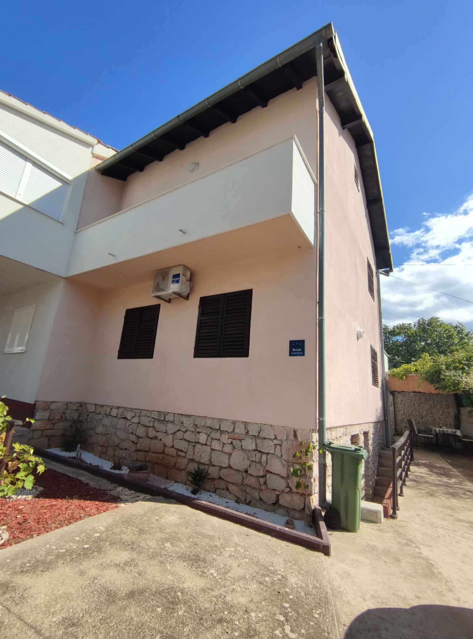A two-story building with a stone foundation, a balcony, and a sign indicating 'Guest Apartments.'