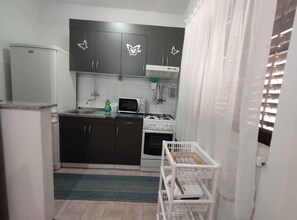 A compact kitchen with dark cabinets, a microwave, a gas stove, and a white refrigerator. - Holiday apartment FLAT DORIANA (2+1) (Srima)