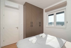 Ein Schlafzimmer mit Bett, Kleiderschrank, Klimaanlage und Fenster mit Blick.