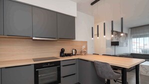 Una cucina moderna con mobili grigi, un piano di lavoro in legno, forno integrato e un angolo bar con una sedia.