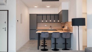 Una cucina moderna con isola centrale, sgabelli da bar e illuminazione a sospensione.