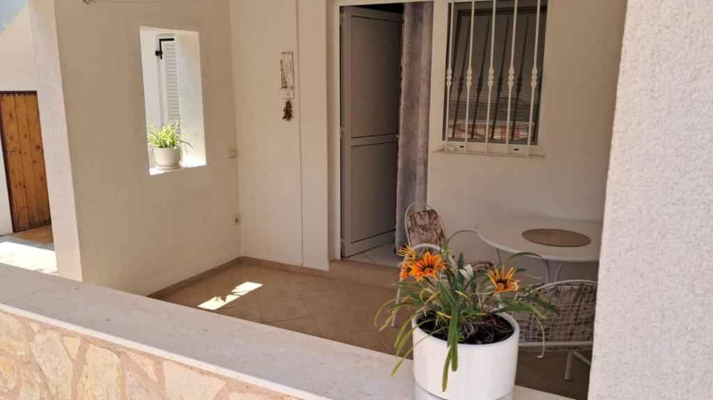 En balkon med en plantekasse, en dør, et vindue med tremmer og et lille bord.