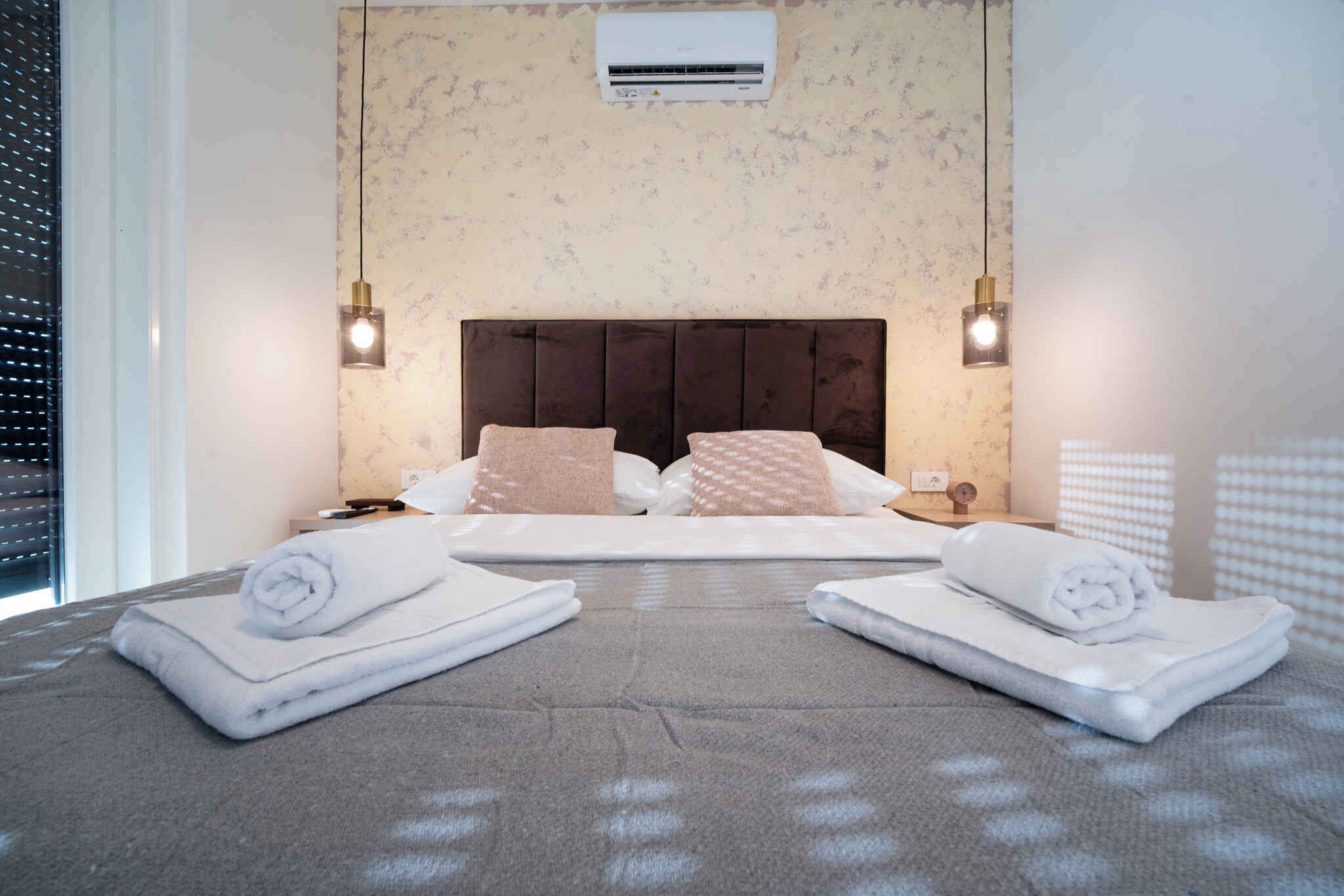 Une chambre d’hôtel comprenant un lit, deux tables de chevet, un appareil de climatisation et une fenêtre avec des stores.