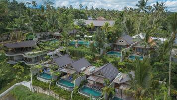 Et resort med flere villaer, hver med egen pool, omgivet af frodig, tropisk vegetation.