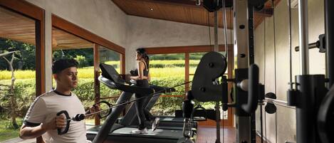 A gym with treadmills, a weight machine, and large windows offering a view of a green landscape.