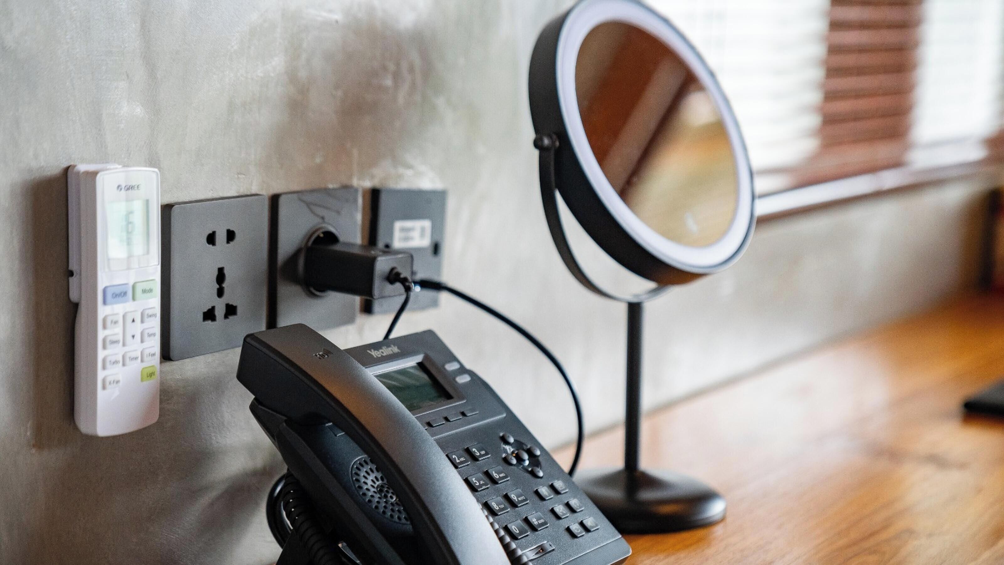 A wall-mounted phone, a power strip, and a mirror.