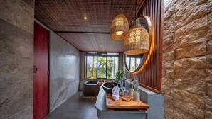Un bagno moderno con una parete in pietra, una porta rossa, un'ampia finestra, un lavandino e un piano d'appoggio in legno.
