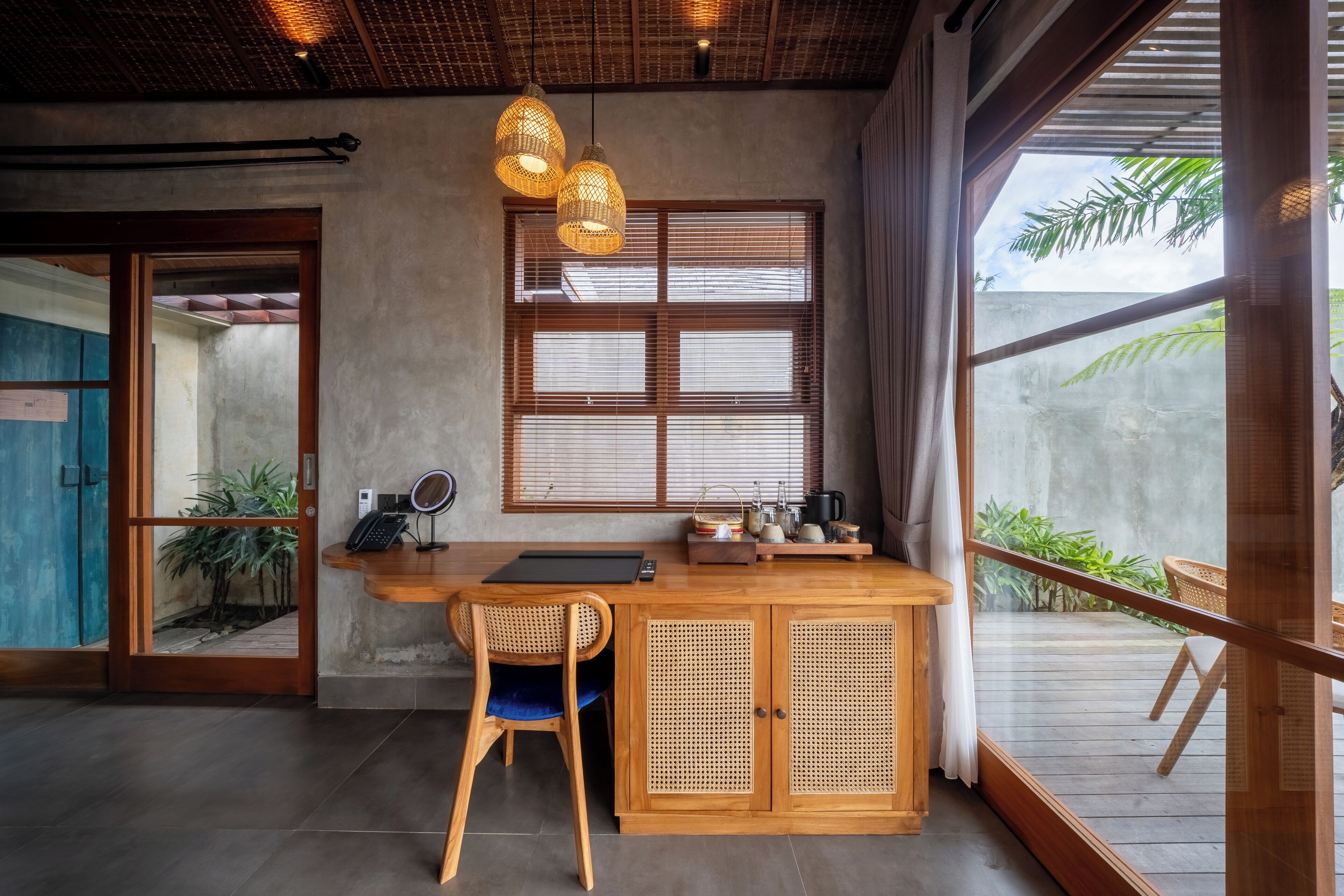 Un escritorio de madera con una silla, una ventana con persianas y una lámpara colgante.