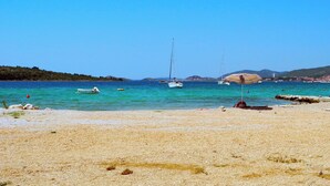 Una platja amb aigua turquesa cristal·lina, un vaixell i un parasol de platja.