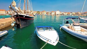 Un port esportiu amb diverses embarcacions amarrades, incloent-hi un veler i un vaixell a motor.