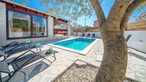A pool area with lounge chairs, a stone patio, and a building with large windows. - Villa VILLA MARIJANA 6+0 (Srima)