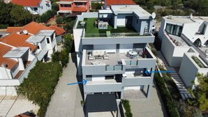 Un immeuble à plusieurs étages doté d’une terrasse sur le toit, d’un espace extérieur couvert avec des sièges et d’un escalier menant aux niveaux supérieurs.