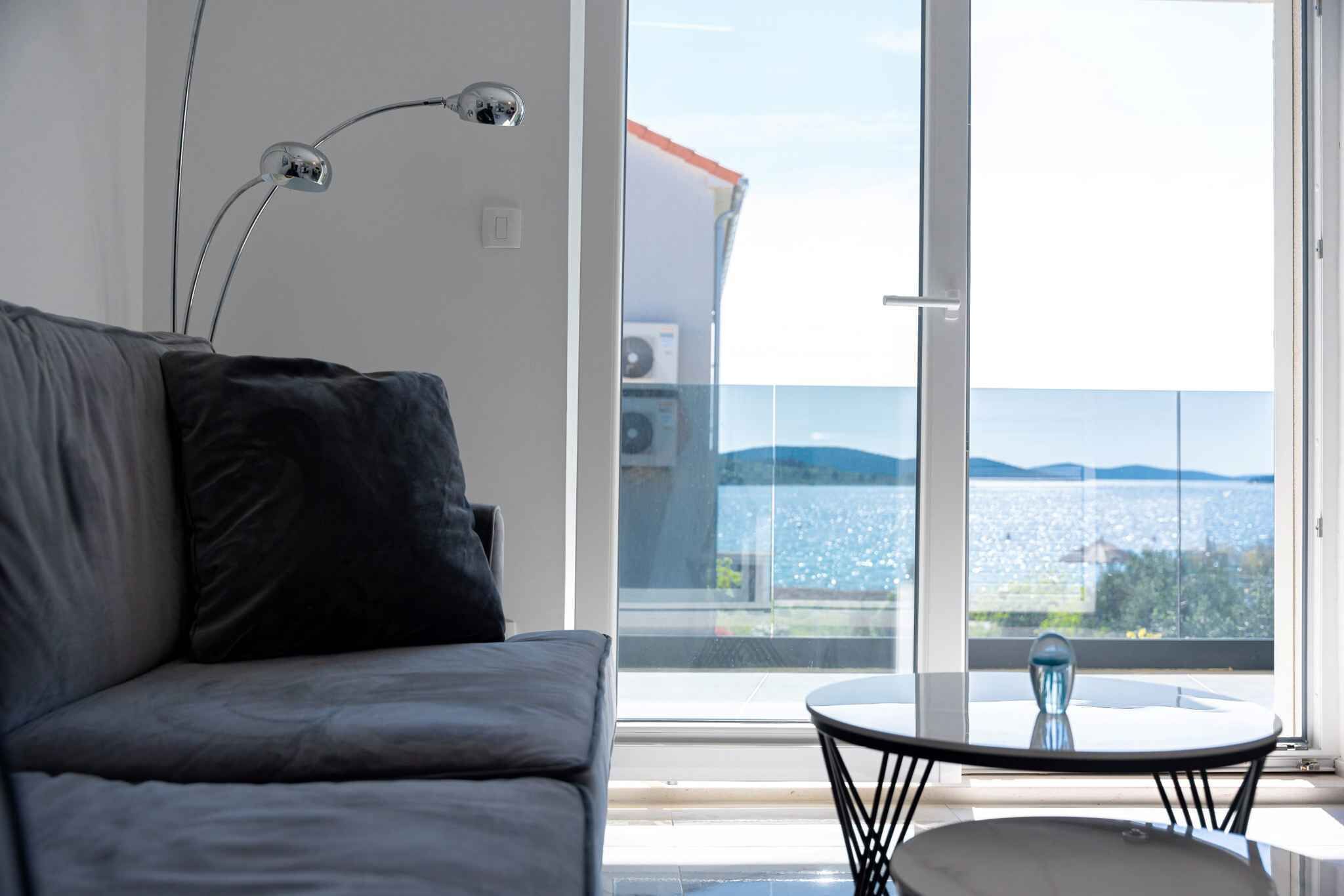 Une chambre moderne avec un canapé, une table et une grande fenêtre donnant sur la mer.