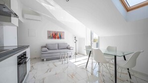 Een moderne keuken met een ingebouwde oven en een eethoek met een glazen tafel en witte stoelen.