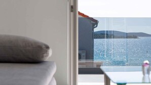 Een kamer met een bed, een glazen tafel en uitzicht op zee.