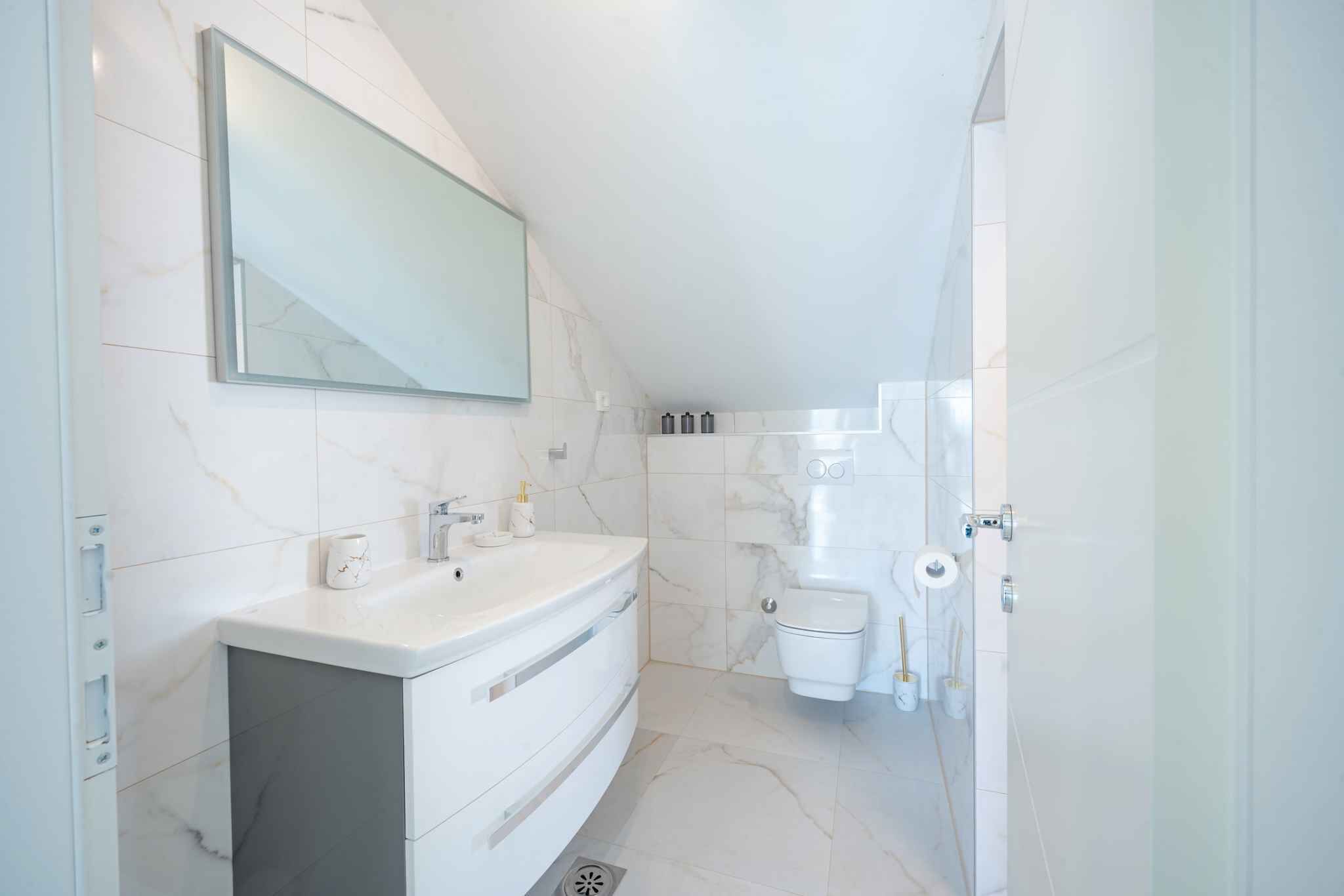 Une salle de bain moderne avec un meuble-lavabo blanc, des toilettes et un espace douche.