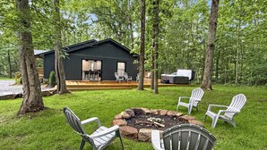 Eine Holzhütte mit einer Terrasse, Sitzgelegenheiten im Freien und einer Feuerstelle.