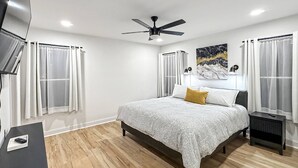 Ein Schlafzimmer mit Bett, Deckenventilator, Fernseher und Schreibtisch.