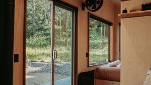 A cozy interior with a sliding glass door leading to an outdoor area, a built-in bench with cushions, and a wall-mounted TV.
