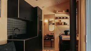 A compact kitchen with dark cabinets, a tiled backsplash, and a central island.