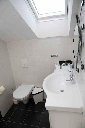 Ein modernes Badezimmer mit Oberlicht, Toilette, Bidet und Waschbecken.