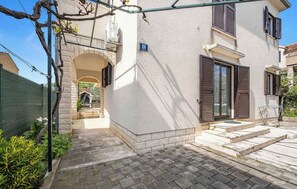 A building with a stone facade, a number '22' sign, a covered entrance, and a paved patio area. - Holiday Apartment GORAN DADIĆ APP 2 (4+0) (Srima)