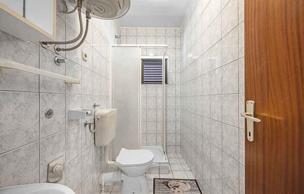 A small bathroom with a toilet, a shower, and a sink.