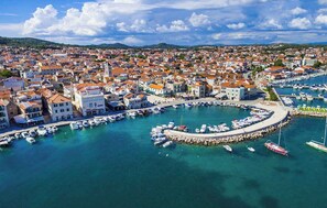 An aerial view of a coastal town with a marina, buildings with red-tiled roofs, and a clear blue sky. - Holiday Apartment GORAN DADIĆ APP 2 (4+0) (Srima)