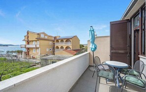 A balcony with a table and chairs, overlooking a body of water and buildings. - Holiday Apartment GORAN DADIĆ APP 2 (4+0) (Srima)