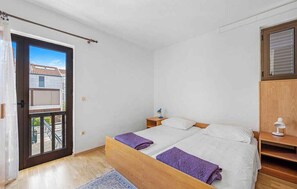 A bedroom with a bed, a nightstand, a window, and a door leading to an outdoor area. - Holiday Apartment GORAN DADIĆ APP 2 (4+0) (Srima)