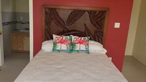 A bedroom with a bed, a wooden headboard, and a red wall.