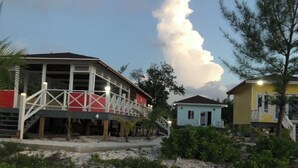 A beachfront property with a covered patio, a small boat house, and a light blue building.