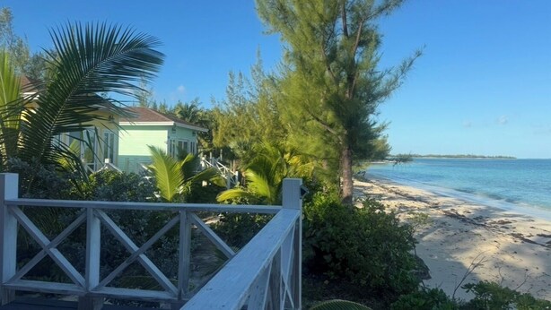 A wooden deck with a view of a beach and a house in the background.