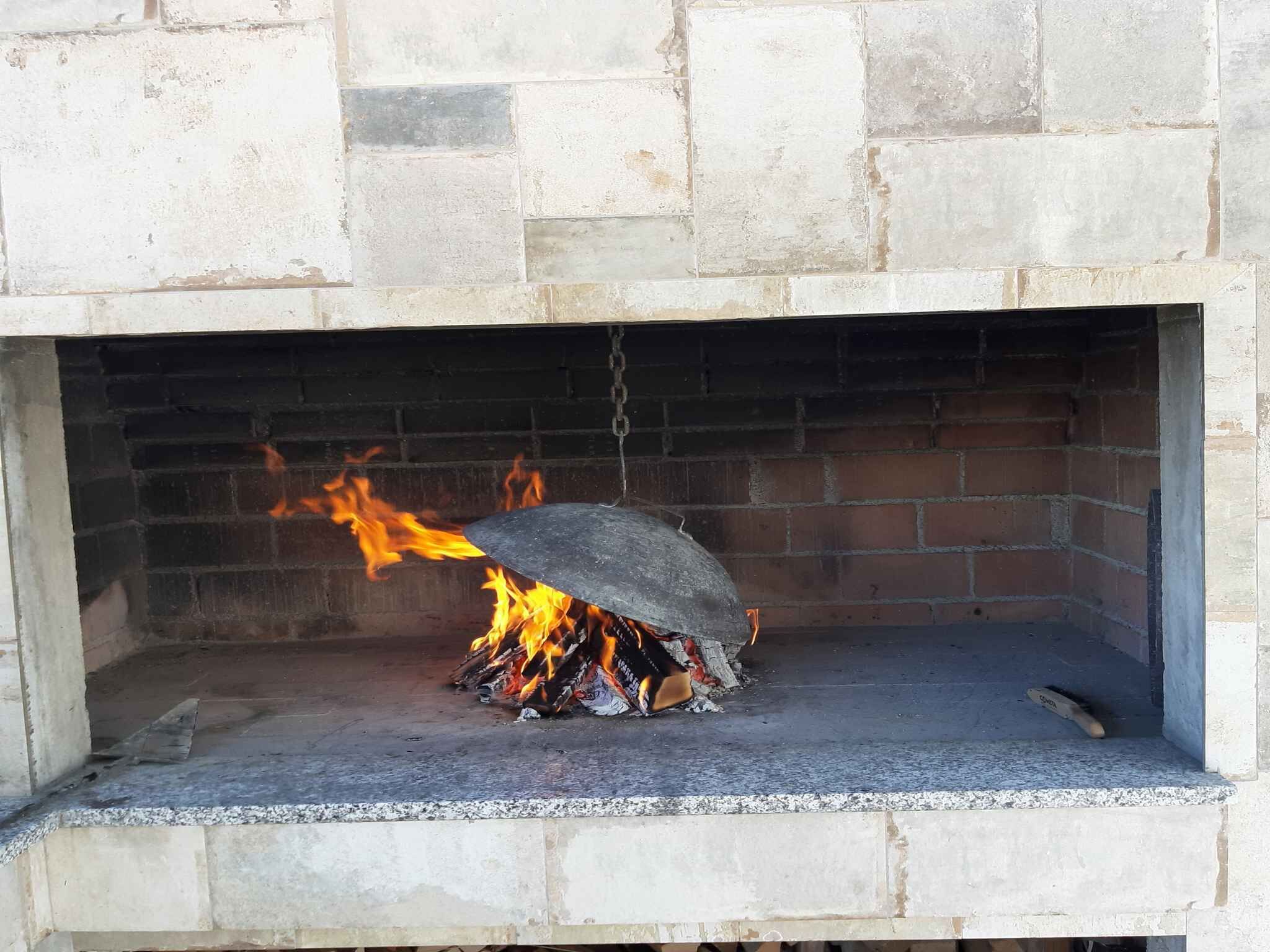 Een stenen open haard met daarin een brandend vuur.