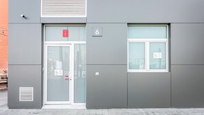 A building with a grey facade, a door with a red sign, a window with a white frame, and a number '6' on the wall. - GuestReady - New apartment in a quiet area (Valencia)