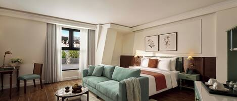 Une chambre d’hôtel avec un lit, un canapé, une petite table et une chaise. Il y a une fenêtre avec des rideaux, une table de chevet avec une lampe et des tableaux encadrés accrochés au mur.