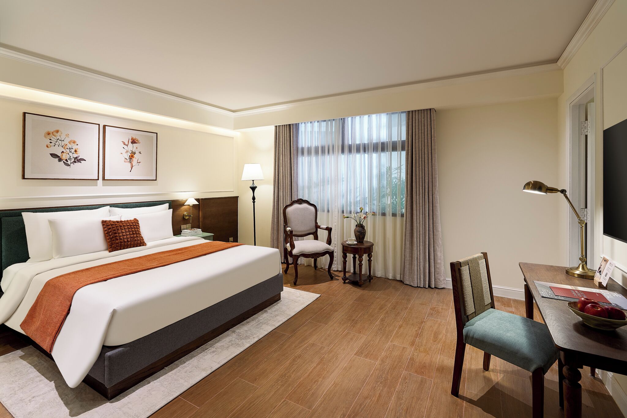 Habitación de hotel con una cama grande, un escritorio con una silla, televisión y obras de arte en la pared.