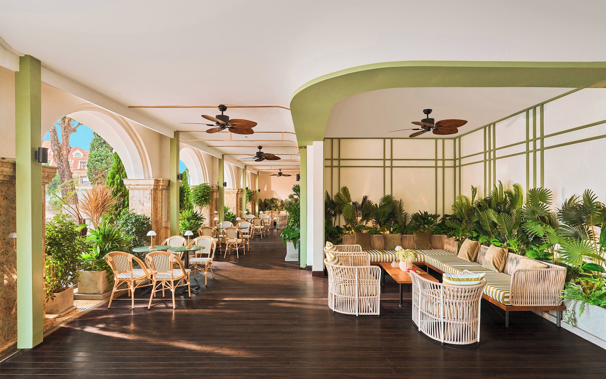 A spacious indoor area with multiple seating arrangements, ceiling fans, and potted plants.