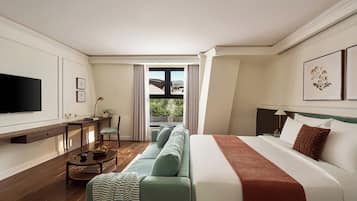 Ein Hotelzimmer mit Bett, einer Couch, einem Fernseher, einem Schreibtisch und Blick ins Freie.