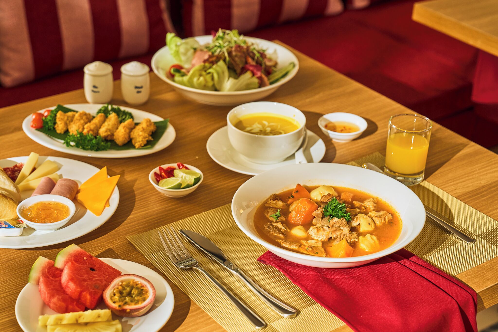 Une table à manger avec différents plats, notamment un bol de soupe, une assiette d’ailes de poulet et une assiette de fruits.