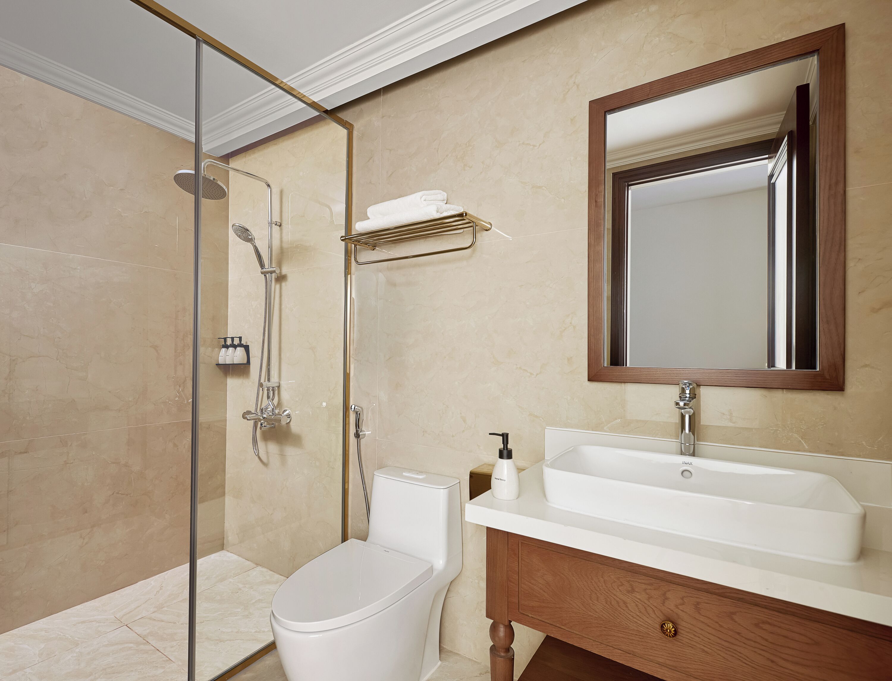 A bathroom with a glass-enclosed shower, a white toilet, a vanity with a sink, and a mirror above the vanity.