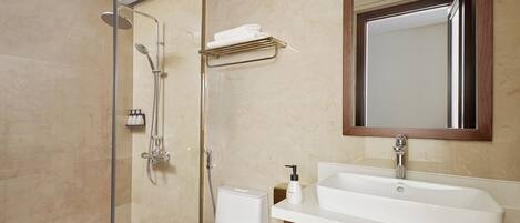 A bathroom with a glass-enclosed shower, a white toilet, a vanity with a sink, and a mirror above the vanity.