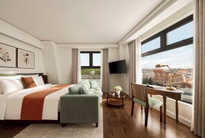 Et hotelværelse med en stor seng, en sofa, et skrivebord og et fjernsyn.