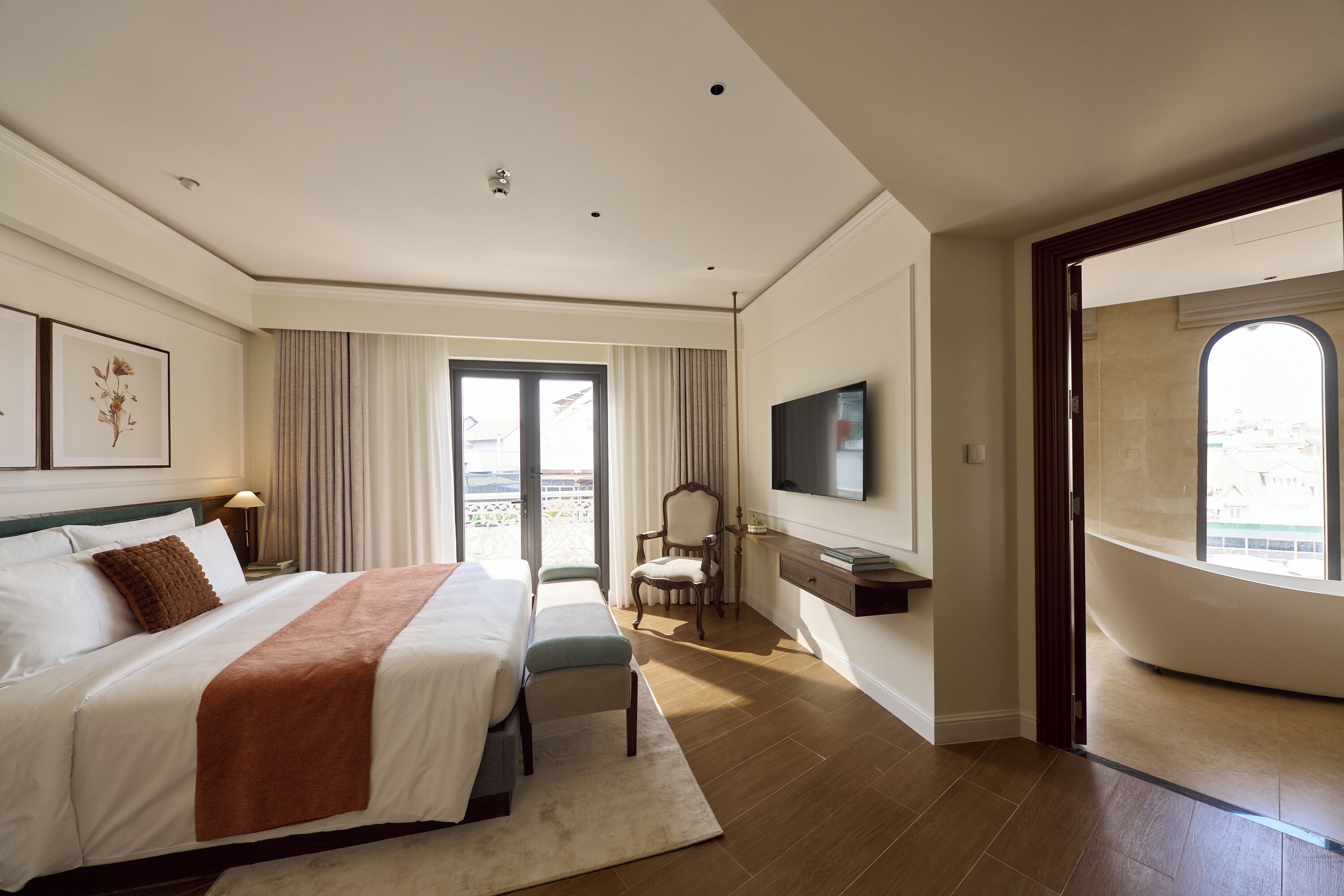 A hotel room with a large bed, a TV, a chair, and a view of the outdoors.