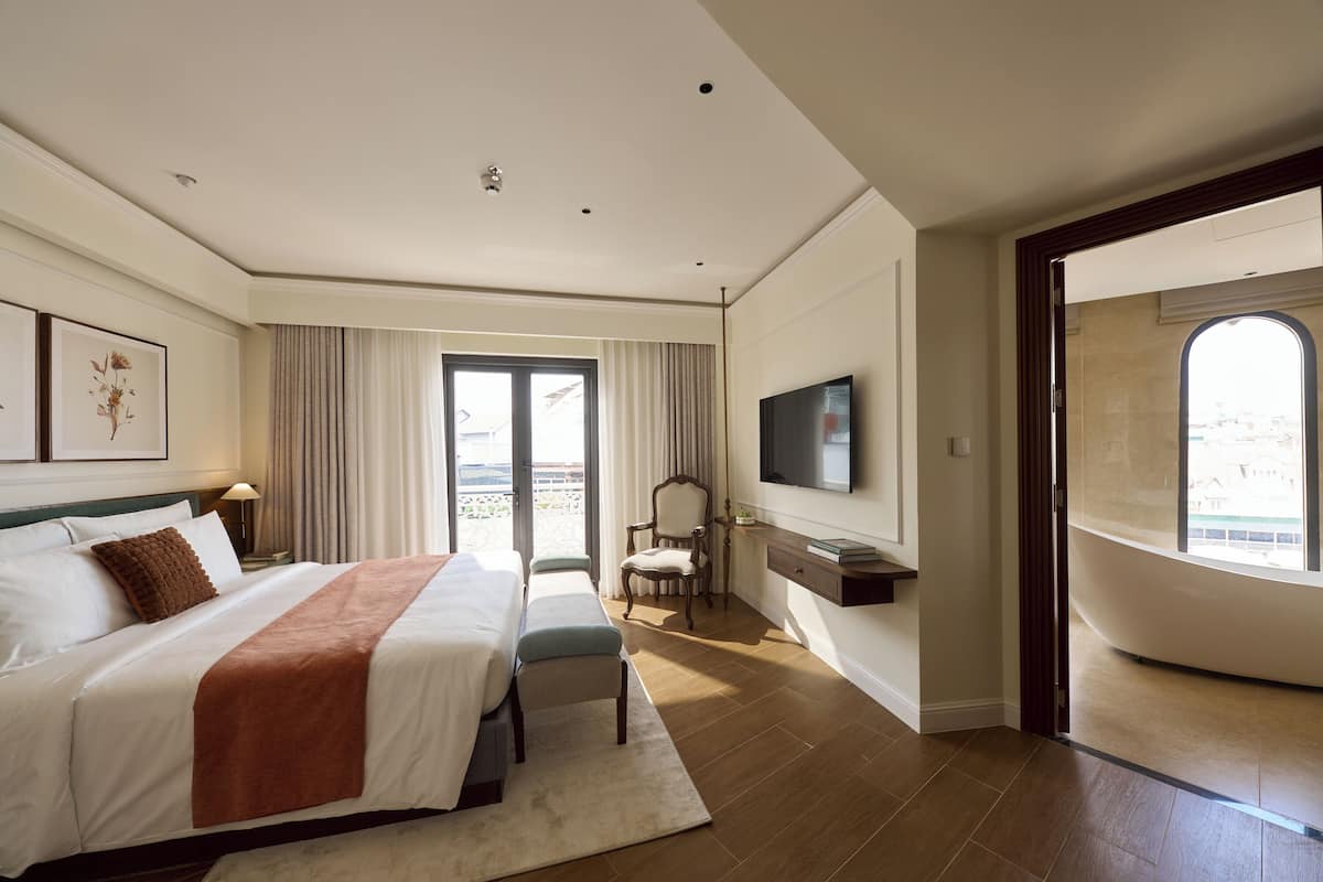 Une chambre d’hôtel avec un grand lit, une télévision, un fauteuil et une vue sur l’extérieur.