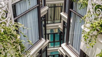 A multi-level atrium with a central staircase, surrounded by balconies with white wrought iron railings and green climbing plants.